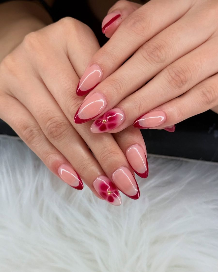 Almond nails with burgundy French tips and a red flower accent